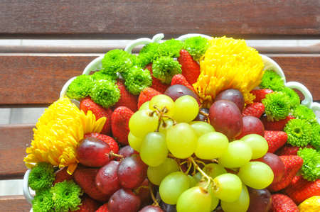 Strawberries and grapes in a basket on the wood tableの写真素材