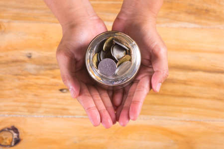 Hand holding jar full of coinの写真素材