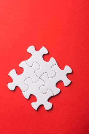 Unfinished white jigsaw puzzle pieces on red backgroundの写真素材