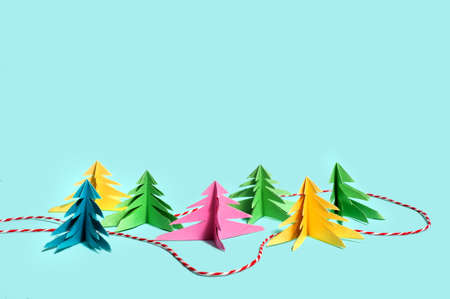 Multicolored paper trees stand against a blue background, and between them, like a path in the forest, a red and white Christmas thread is laid. Copy space. Top view. Mindfulnessの写真素材