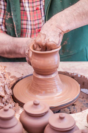 Hands of a potter molding the clay to make pots, vases, dishes ...の写真素材
