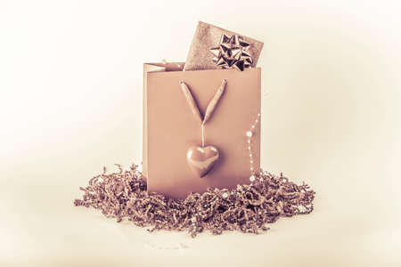 Beautiful pink surprise present bag with love symbol heart. Wonderful vintage gift with a card inside maybe voucher or concert tickets for Valentine's Day or Mother's Day. Isolated on white backgroundの写真素材