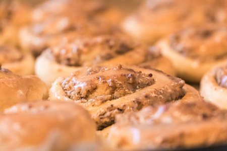 Tasty cinnamon rolls pastry with sugar frosting nuts stuffing. Delicious leavened dough pastries for breakfast, dessert or brunch. Yummy juicy backed traditional goods from bakery or confectionery.の写真素材