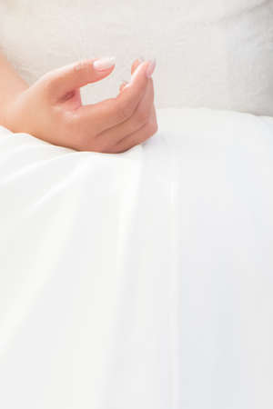 Wedding bride hand with luxury bright dress at marriage ceremony. Elegant stylish engagement wife with nails polished. Woman is waiting for ring and vow. Romantic love scene with large white copyspaceの写真素材