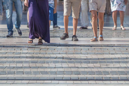 Pedestrian crossing downtown city crowd walk in motion on road. Many legs, feet and shoes from different people walking on town street crosswalk in a hurry pace urban day lifestyle. Large copyspace.の写真素材