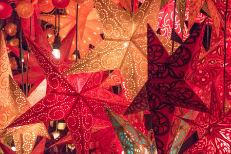 Group red golden orange xmas lantern stars at christmas market. Traditional shopping decoration at...