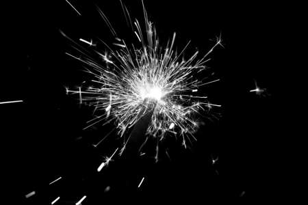 White sparkler countdown on fire with spread of glitter sparks. Luxury entertainment at eg New Years Eve, Independence Day or birthday party celebration. Glowing light spark on dark background.の写真素材