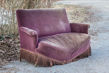 Aged used luxury couch of history memories telling past stories. Sofa is taken out of service because of damaged disused seat surface. Old design furniture broken from overweight encounters meetings.の写真素材