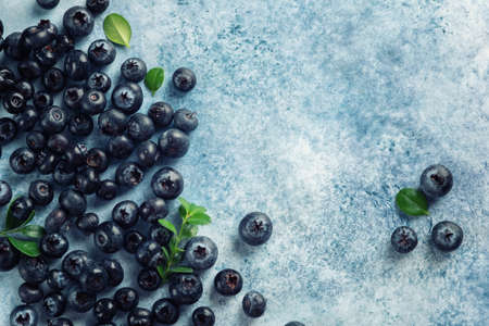 Fresh juicy blueberries with green leaves on blue background.の写真素材