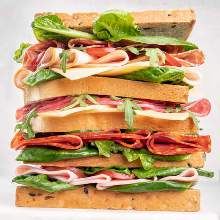 Big tasty sandwich with ham, salami, salad, cheese and tomatoesの写真素材