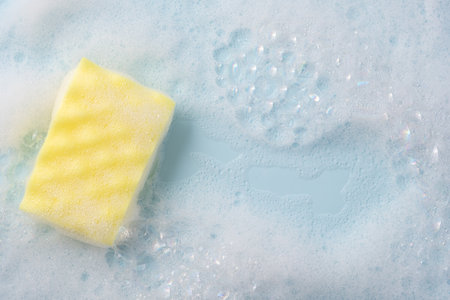 Cleaning sponge and a soapy foam on a blue background.の写真素材