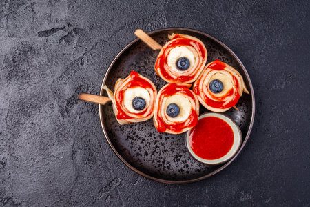 Monster Bloody Eyeballs for Halloween. Crepes roll up with banana and strawberry jamの写真素材