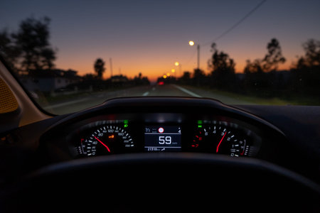 Driver view to the speedometer at 59 km/h or 59 mph, on a road blurred in motion, night fall view...
