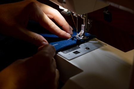 Female hands of a master tailor working with blue denim weave
