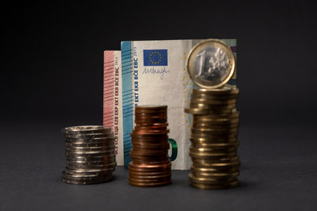 Euro banknotes on a dark background. Twenty euro banknote concept with euro coins stacked in front and out of focus. Copy space.の写真素材
