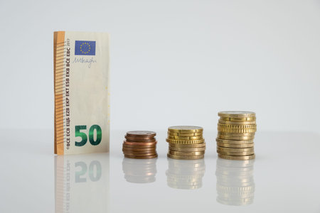Fifty euro banknote and euro coins stacked on a white background. Euro money savings concept. Copy...