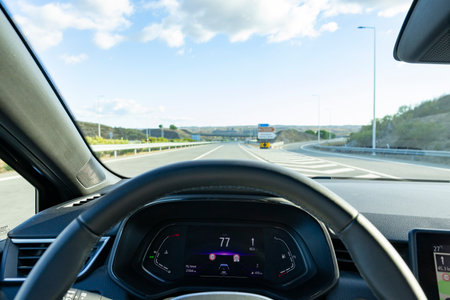 Speedometer in the car on the dashboard. The car's speedometer shows 77 Km's per hour (Seventy seven Miles per hour), with the empty highway in the background. Algarve, Portugal.の写真素材