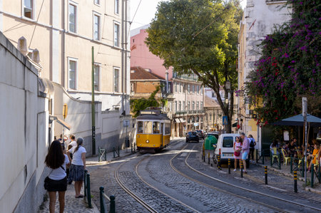 Lisbon, Portugal - 18.09.2023 View of a typical street in Santa Maria Maior in Lisbon downtown, with cars, electric train and people. City of Lisbon, Portugalのeditorial素材