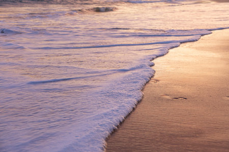 Soft wave of the sea on the sandy beach at sunset time.