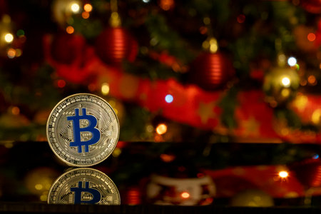Bitcoin coin with reflection on on blurred christmas tree background. Cryptocurrency and digital money concept.の写真素材