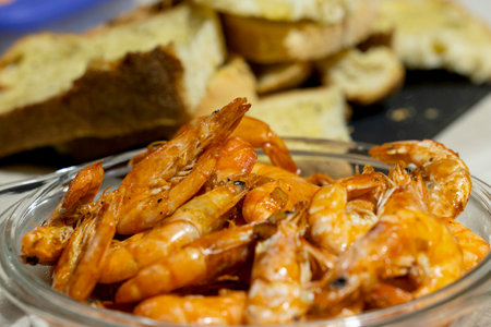 Grilled shrimp with garlic in a glass bowl with toasted bread on the background.の写真素材