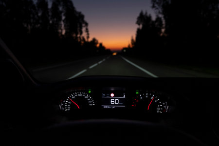 Driver view to the speedometer at 60 km/h or 60 mph, on a road blurred in motion, night fall view from inside a car of driver POV of the road landscape.の写真素材