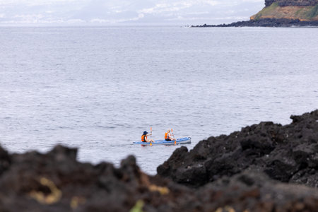Couple of friends Kayaking in the Atlantic Ocean on the Volcanic Coast of island of Sao Miguel, Azoresの写真素材