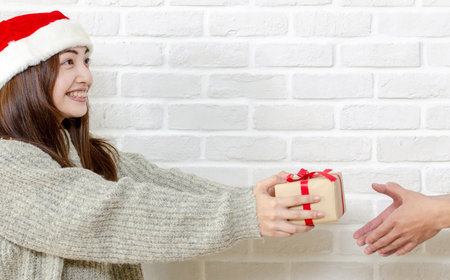 Smiling asian young woman gets gift box from other's hand