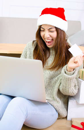 Smiling young asian woman shops online with credit card at Christmas dayの写真素材