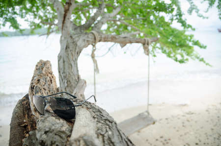 The seat is made of wood tied to a tree with glasses on the beach.の写真素材