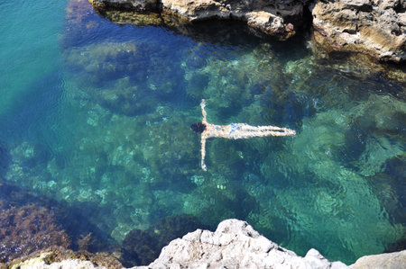 Silhouette of the girl swimming in the blue sea, summer day.