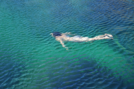 Silhouette of the girl swimming in the blue sea, summer day.の写真素材