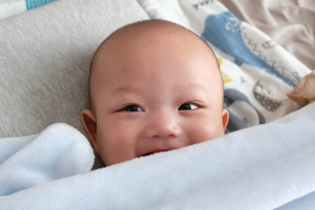 Portrait of cute asian baby lying on bed, closeupの写真素材