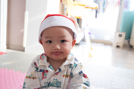 Cute asian baby boy in santa claus hat at home