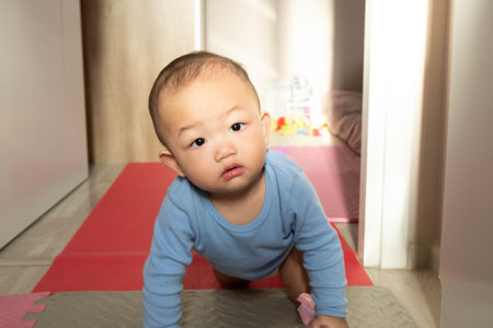Cute asian baby boy doing push-ups at home.