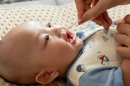 Mother holding a spoon feeding her baby boy. Mother feeding her son with a spoon.の写真素材