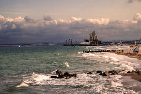 Cargo cranes and sea under the stormy sky in sunsetの写真素材