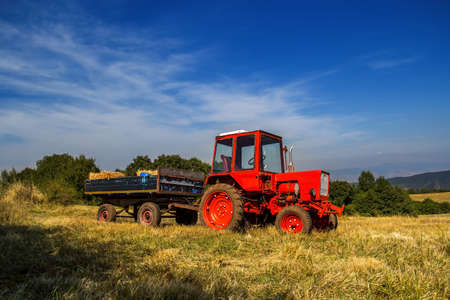 Old red tractor on the agricultural field in autumnの写真素材