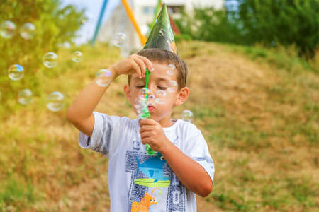 little boy playing with soap bubbles in summer