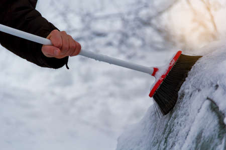 closeup of man cleaning snow from car in winterの写真素材