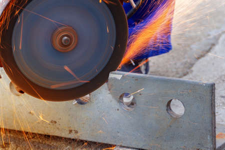 worker with angle grinder cutting steel