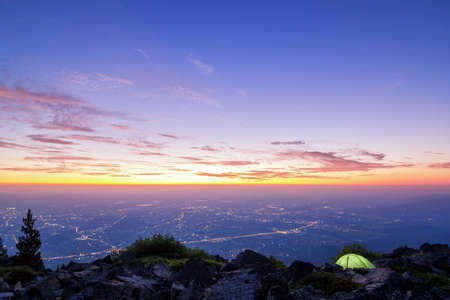 camping in the mountains and beautiful sunrise over the city in Europeの写真素材