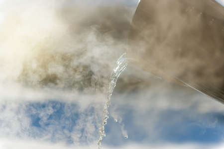 Pouring hot water in winter at sunsetの写真素材