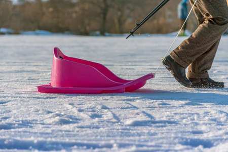 person pulling sledge on the mountain road in woods at sunset