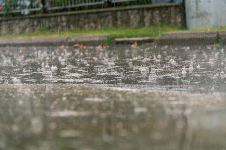 heavy rain drops falling on city asphalt during downpour in autumnの写真素材