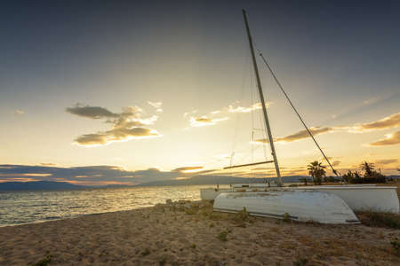 Sailboat on the beach at sunset in Greeceの写真素材