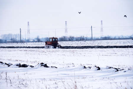 Crawler Tractor plowing field in winter.の写真素材