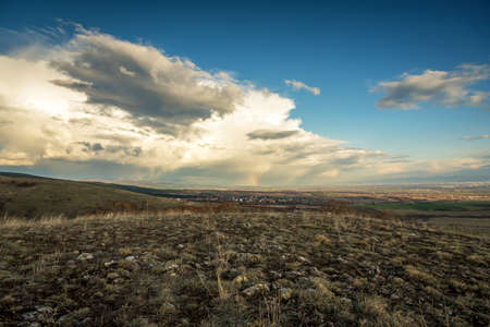 Village in valley on cloudy rainy day. Panoramic landscape of village with multi colored roofs.