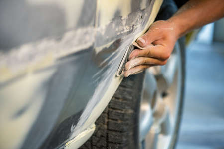 Grinder in the hands of a man who sharpen a car varnish in the car shop.
