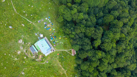 Rai hut surrounded with fresh green mountain pastures with blooming flowers.
